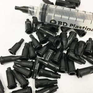 A collection of black Luer Lock End Caps scattered around a plastic syringe, commonly used in mycology to seal syringe tips.