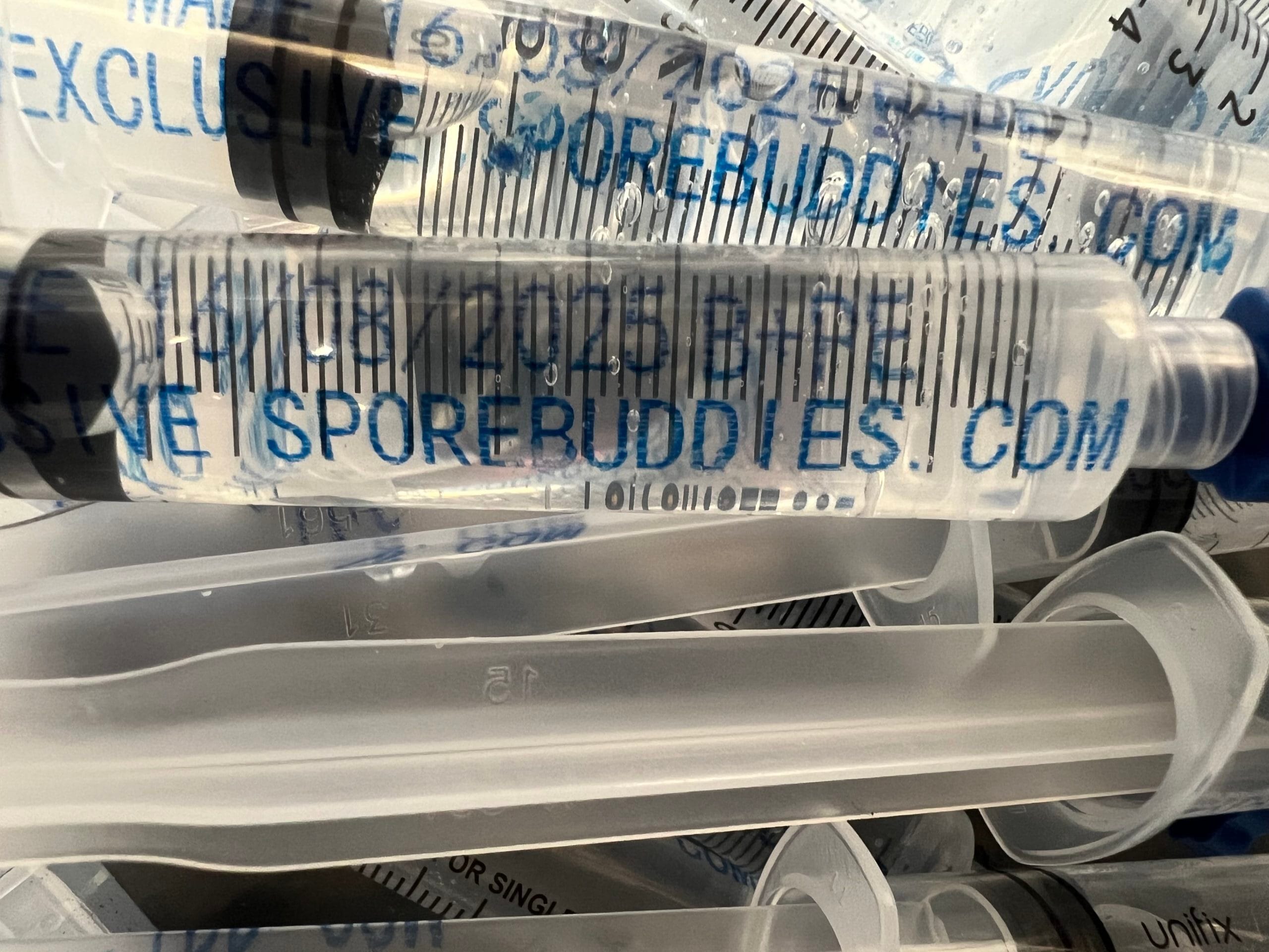 Spore syringe sample prepared for microscopy workflows, showing a labelled syringe and sterile presentation.