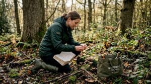 Forager using mushroom guide in UK woods
