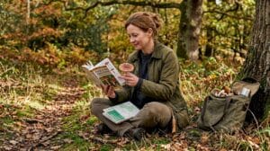 Woman studying mushroom guide in autumn woods
